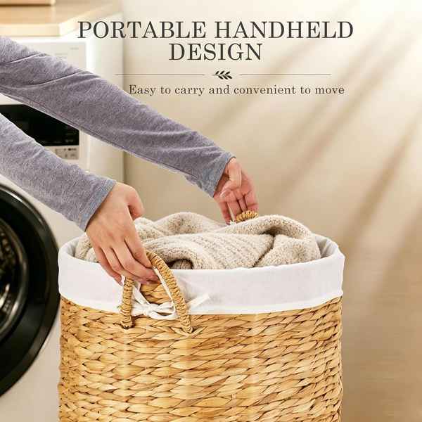 A woven straw laundry basket with a white fabric liner and two carry handles, shown being filled with beige towels. A person&