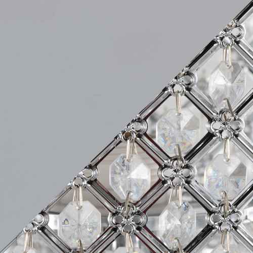 Close-up detail of a faceted crystal chandelier panel with clear glass prisms and silver metal frames on a gray background.