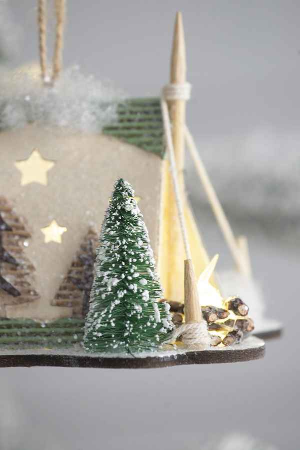Decorative Christmas scene with a small tree, logs, and a snowy landscape.