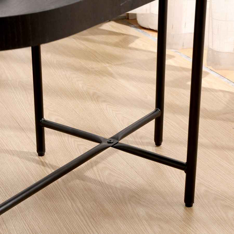Close-up of a black metal chair leg on a wooden floor