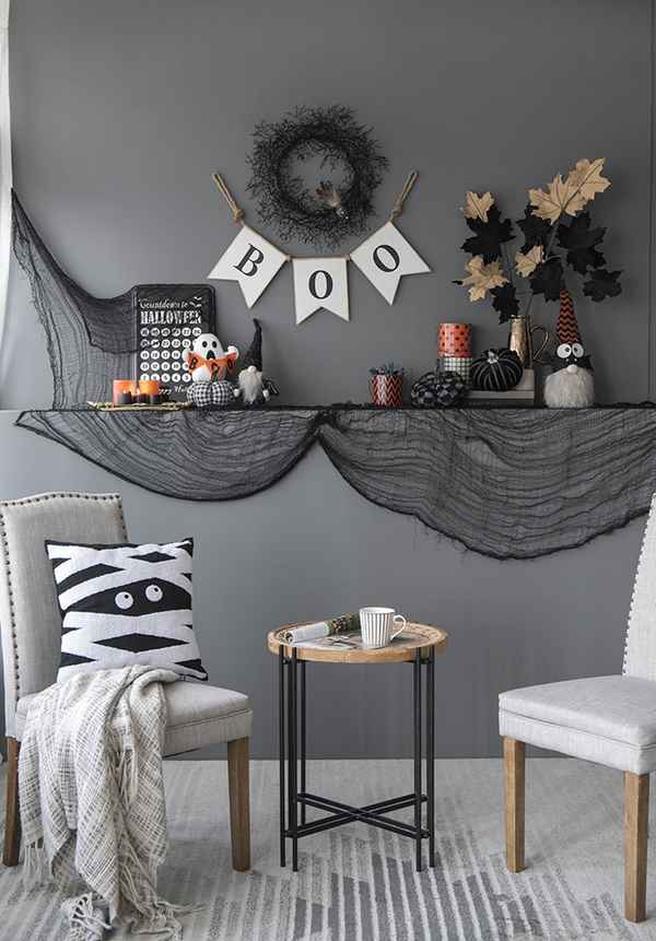 Halloween-themed room decor with a mantel, chairs, and decorative items.