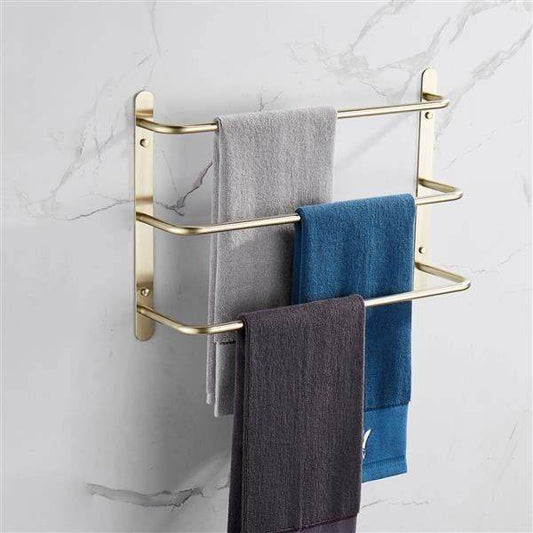 Gold wall-mounted towel rack with three colorful towels on marble bathroom wall