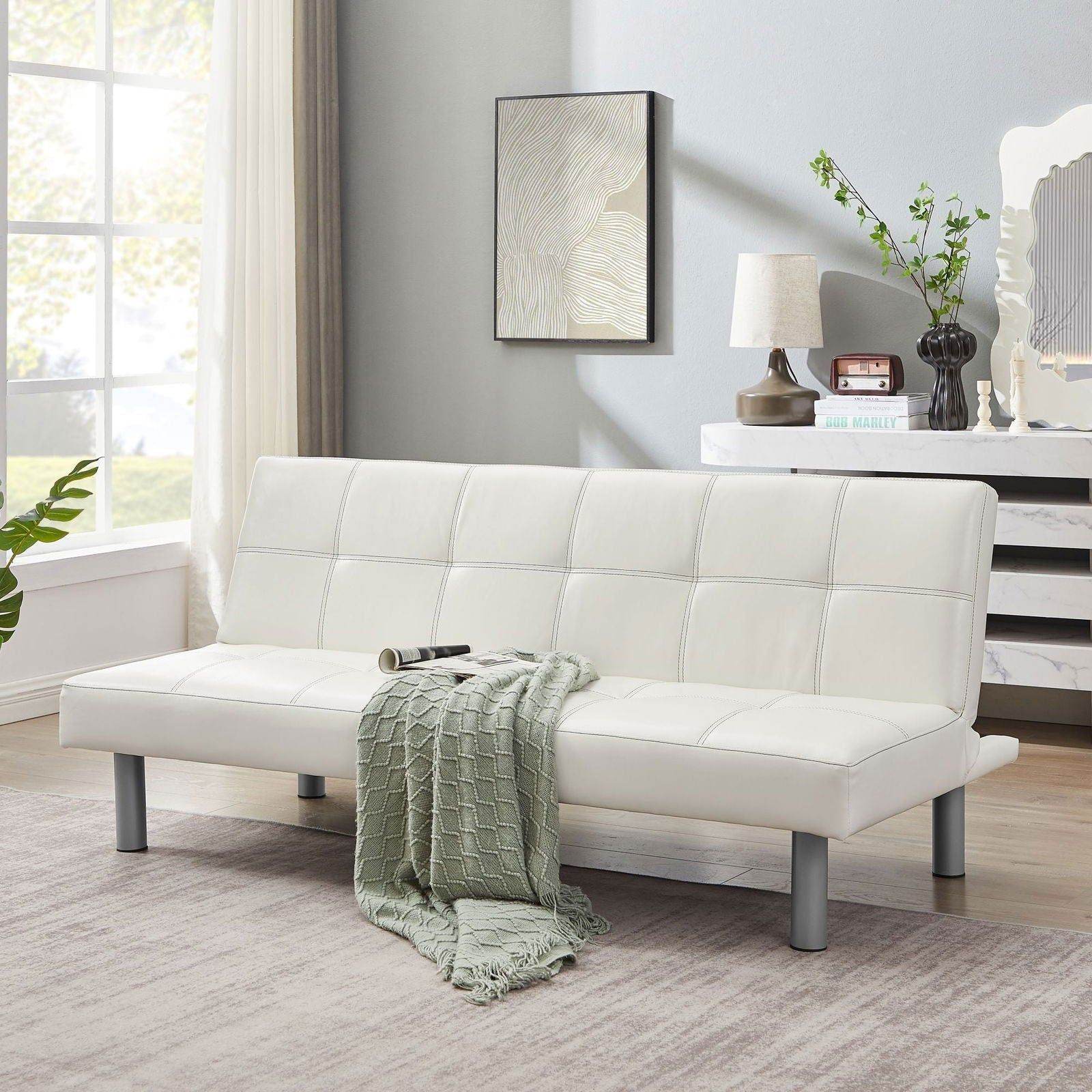 Modern white futon sofa bed in bright living room with green throw blanket