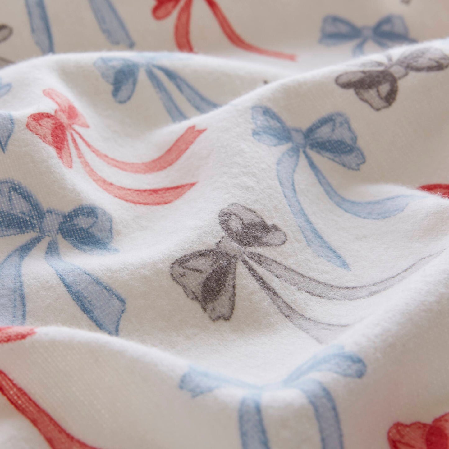 Detailed fabric texture of Happy Bows flannel sheet with soft brushed cotton and multicolor bow print.