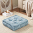 Blue cushion on a beige carpet with a candle and books in the background