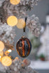 Egg Christmas ornaments in black and gold hanging with lights