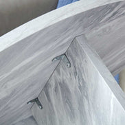 Underside view of MDF white round coffee table showing metal brackets securing the tabletop to the cross-panel base.