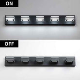 A six-light wall-mounted light bar shown in two states: ON at the top, emitting bright white light, and OFF at the bottom, turned off with no light. The fixture is matte black with silver accents on the light heads, set against a split gray and white background.