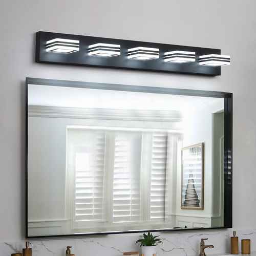 A modern black rectangular wall-mounted light fixture with five square-shaped illuminated shades, positioned above a large rectangular mirror with a black frame in a bathroom setting.