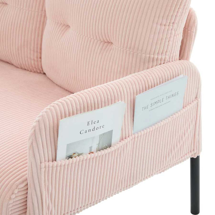 Pink corduroy chair with magazine holder containing books.