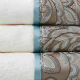 Close-up of Elegant Jacquard Towel Set showing detailed taupe paisley jacquard border and smooth blue satin trim on soft cotton.