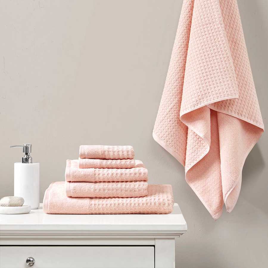 Cotton Antimicrobial Bath Towel Set in pink displayed on a white vanity with one towel hanging, showcasing quick-dry and odor control features.