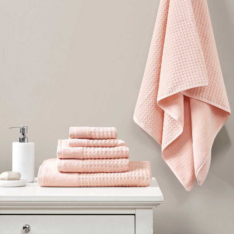Cotton Antimicrobial Bath Towel Set in pink displayed on a white vanity with one towel hanging, showcasing quick-dry and odor control features.