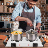 Person cooking on dual burner electric stove with steaming pot
