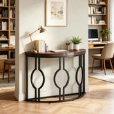 A curved console table with a dark wood top and black metal frame featuring three large interlocking oval motifs, styled in a home office setting.