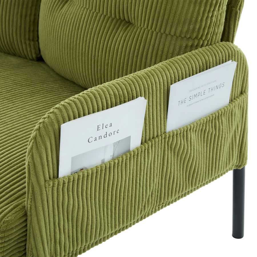 Green corduroy sofa with magazine holders containing books.
