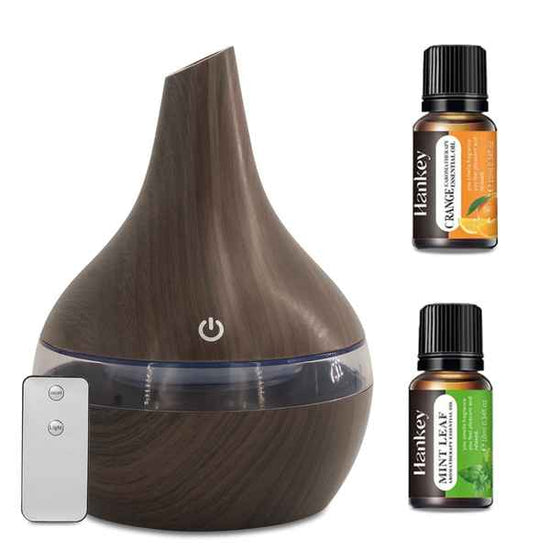 Wooden diffuser with remote control and two essential oil bottles on a white background