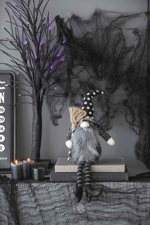 Whimsical Halloween gnome decor with tall black hat, long striped legs, gray beard, and cozy outfit, perfect for seasonal home decoration.