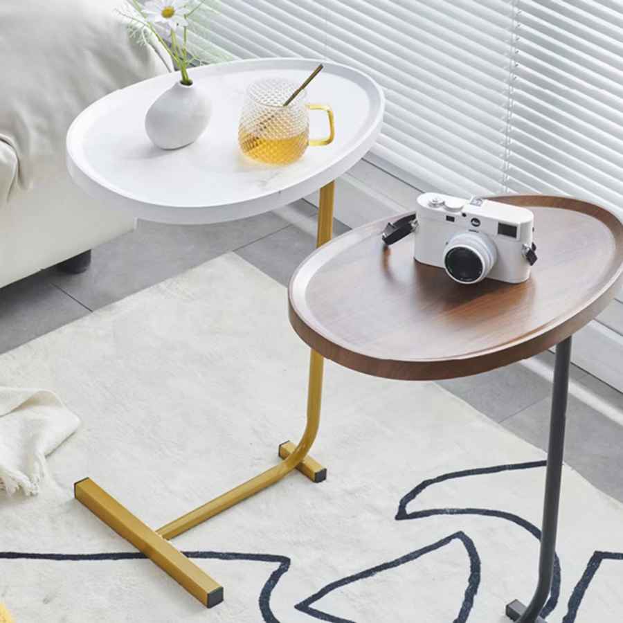 Two side tables, one white and one brown, with a camera and mug on a rug.