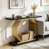 A modern hexagonal console table with a black marble-look top and base, and a gold-toned geometric slatted frame, styled in a living room next to a gray sofa.