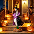 A decorative goose figurine dressed as a witch stands on a front porch staircase decorated with glowing jack-o&