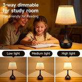Woman and child at a table with a 3-way dimmable lamp, showing different light settings.