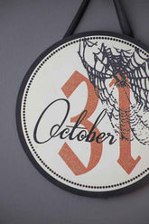 Close-up of Halloween circle sign with October 31 date, spider web, black ribbon, and dotted border, suitable for seasonal decor