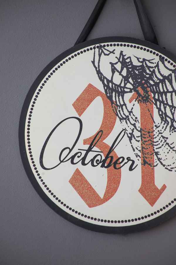 Close-up of Halloween circle sign with October 31 date, spider web, black ribbon, and dotted border, suitable for seasonal decor