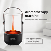 A black aromatherapy lamp with a clear glass top, copper-toned handle, and orange flame effect inside, shown on a white surface with promotional text reading &