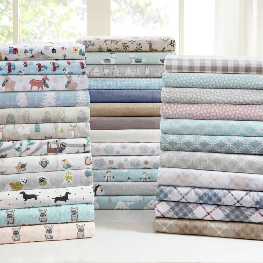 Assorted printed flannel sheet sets stacked in various colors and patterns, including the 3 PCS Twin XL Printed Sheet Set with White Village Print.