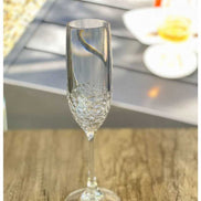 Durable 6oz unbreakable plastic champagne flute on wooden surface, showcasing elegant design with textured lower bowl.