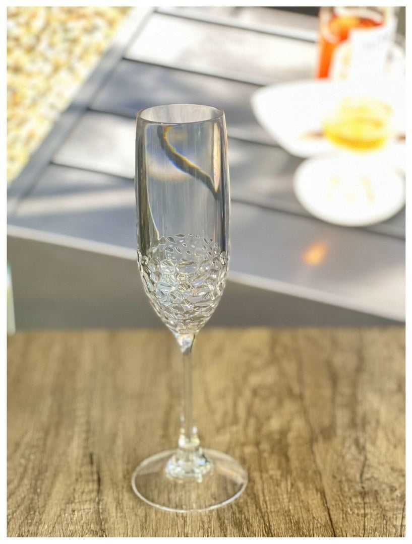 Durable 6oz unbreakable plastic champagne flute on wooden surface, showcasing elegant design with textured lower bowl.