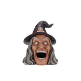 Side view of Halloween witch head with glowing eyes, open mouth, long gray hair, purple hat with skull, spooky Halloween scene