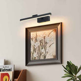Modern wall light fixture above a framed artwork on a wall.