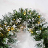 Decorative wreath with greenery and small lights on a white background