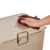 Hand cleaning a beige suitcase with a brown cloth on a white background
