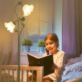 Child reading a book in a cozy bedroom with a flower-shaped lamp.