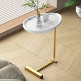 White side table with gold legs in a room with wooden flooring and a plant.