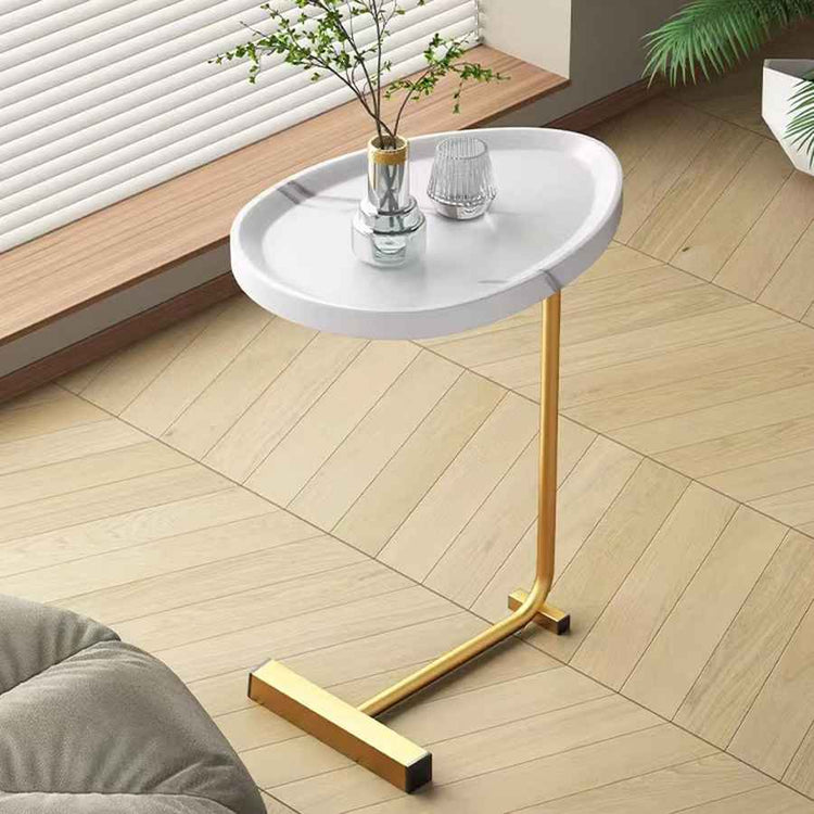 White side table with gold legs in a room with wooden flooring and a plant.