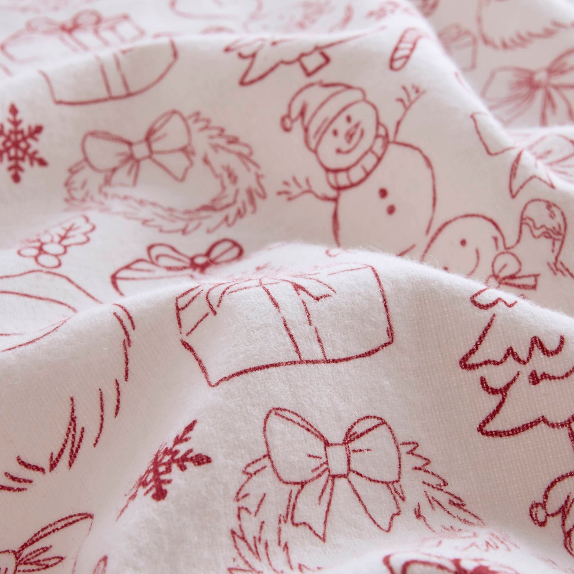 Close-up of soft cotton flannel fabric with red holiday doodles, showcasing the cozy texture of the Twin XL sheet set.