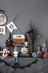 Halloween-themed decorations on a shelf against a gray wall.