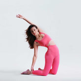 Woman in pink athletic wear posing against a light gray background