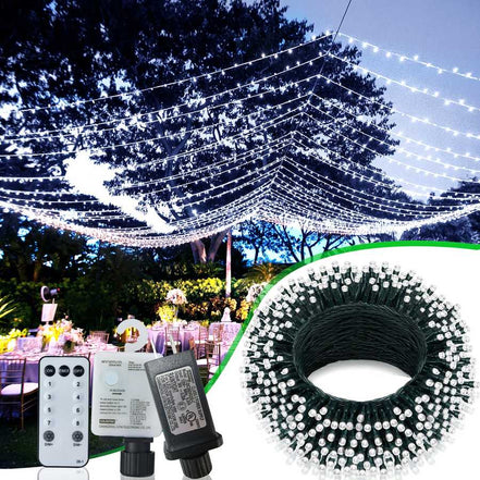 String lights with remote control and power adapter, set up outdoors with trees and tables in the background.