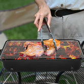 Person grilling fish on a portable barbecue grill outdoors.