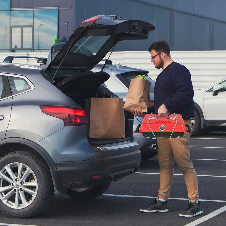 Man loading groceries into a car trunk in a parking lot