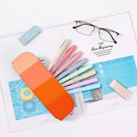 Set of colorful pens in an orange case on a magazine with glasses and a USB drive.