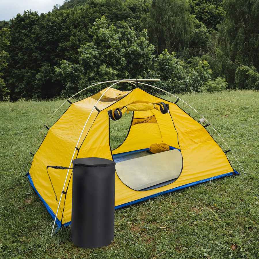 Yellow camping tent with a black trash can on grass with trees in the background