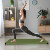 Woman practicing yoga on a green mat in a home setting