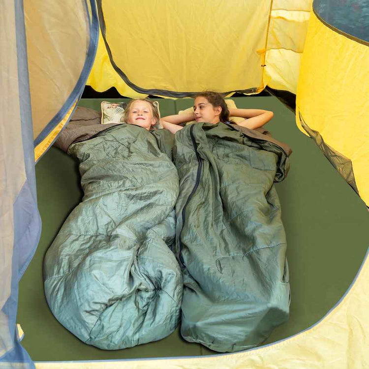 Two people lying in green sleeping bags inside a yellow tent.