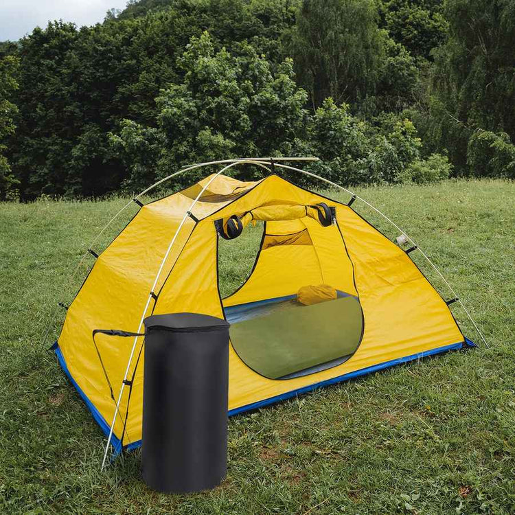 Yellow tent with a black trash can on grass with trees in the background